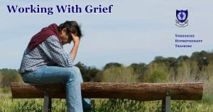a man sitting astride a wooden bench, his head in his hands, overcome with grief