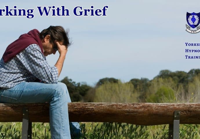 a man sitting astride a wooden bench, his head in his hands, overcome with grief