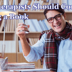 Why Therapists Should Consider Writing a Book a therapist sat at a desk writing a book